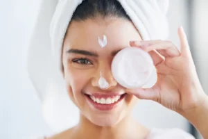 Happy girl applying skincare products during her daily skincare routine for healthy glowing skin.
